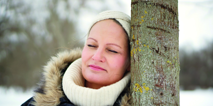 Frau lehnt an Baum