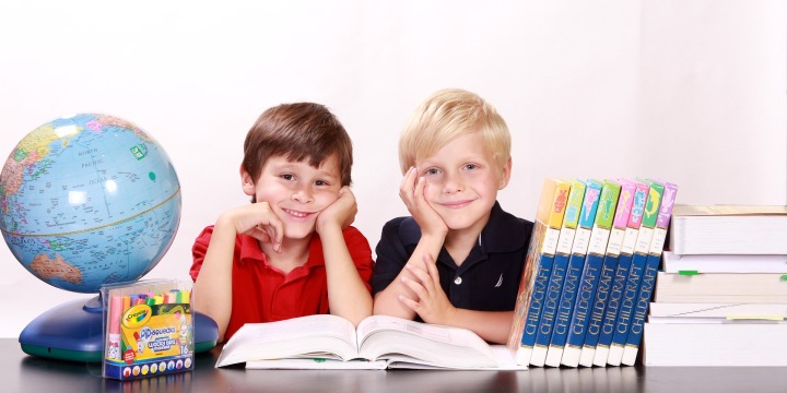 Zwei Jungen sitzen am Tisch mit Büchern und Länderflaggen