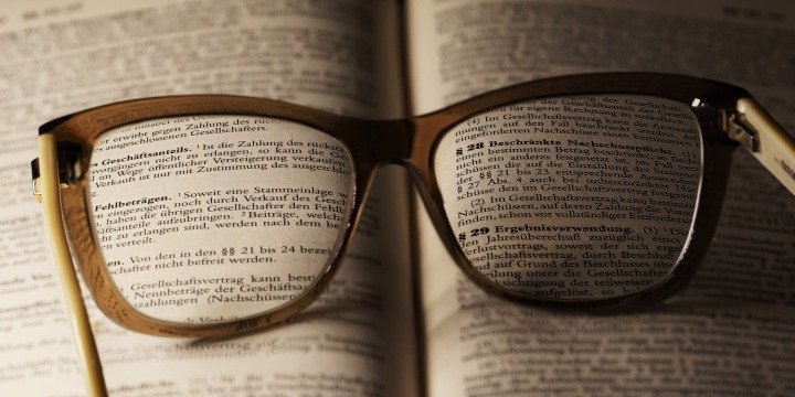 Brille liegt auf aufgeschlagenem Buch