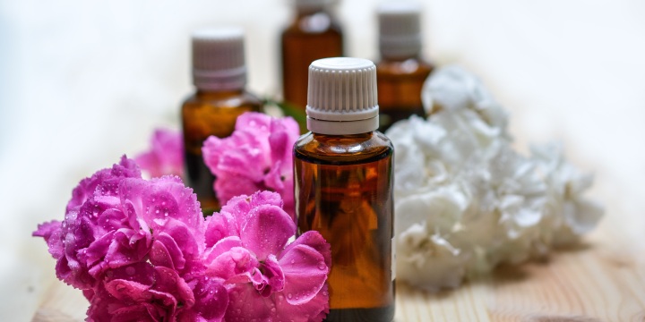 kleine Fläschchen mit Aromaöl, umringt von Blumen