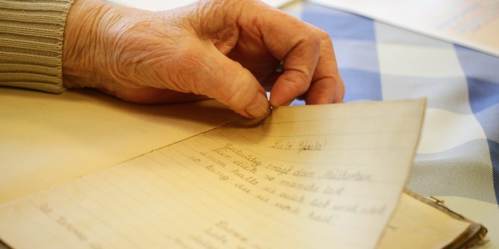 Ein altes Schriftstück liegt auf einem Tisch und eine Hand hält dies fest