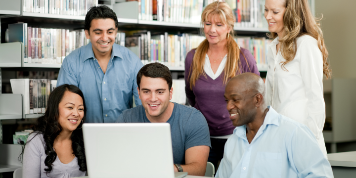 viele Natopnalitäten welche vor einem Laptop sitzen und hinein schauen