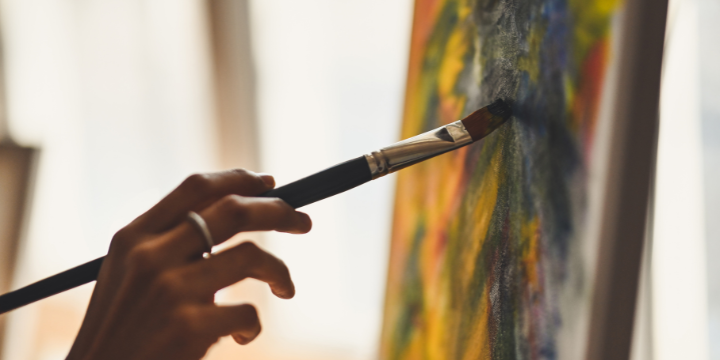 Hand mit Pinsel und Farbe an einer Leinwand