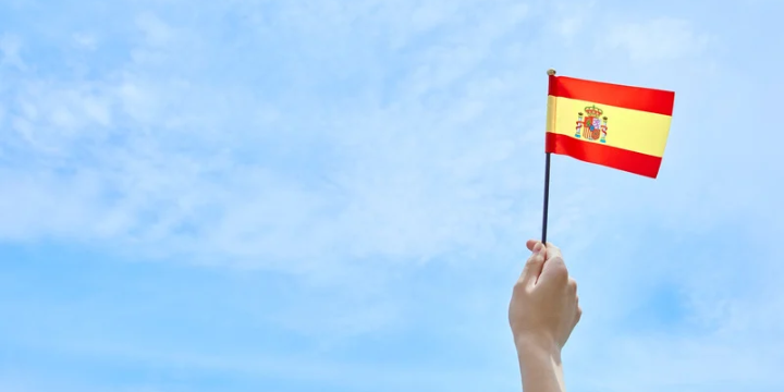 Eine Person hällt die spanische Flagge in den Himmel.